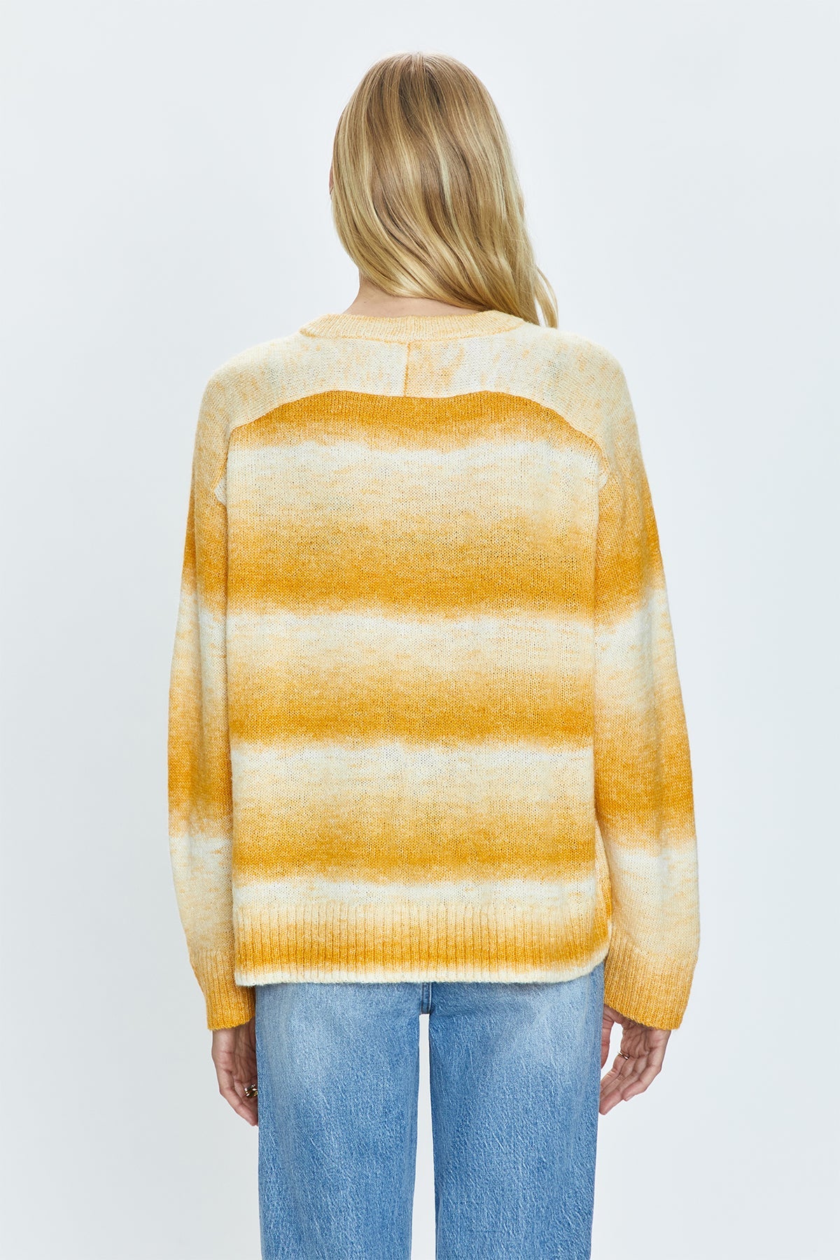 Lightweight transitional sweater crafted from a knit blend with a touch of wool. Crewneck silhouette with long sleeves, raglan shoulders, and a relaxed fit. Sunset is a dip-dye striped color effect featuring warm shades of ivory, yellow, and orange.