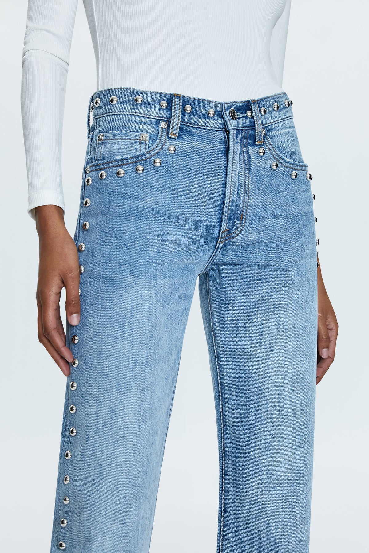 Mid-rise, with a straight leg that bows at the knees for an arched, barrel leg silhouette. Ankle length crop with a clean finish hem, crafted from rigid non-stretch denim for an expert fit that holds its shape. Satellite is a light blue denim wash with vintage fading, defined by linear stud decorations along both legs, waistband, and front pockets.