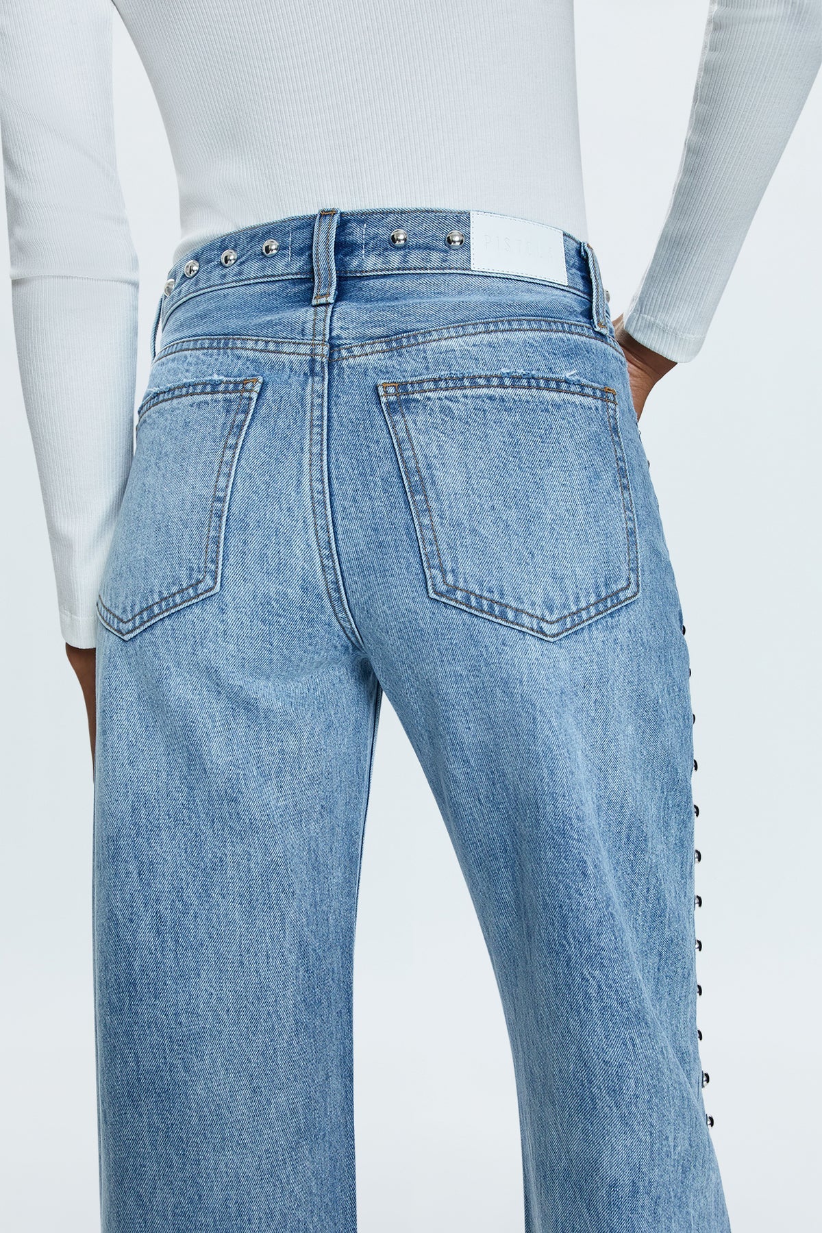 Mid-rise, with a straight leg that bows at the knees for an arched, barrel leg silhouette. Ankle length crop with a clean finish hem, crafted from rigid non-stretch denim for an expert fit that holds its shape. Satellite is a light blue denim wash with vintage fading, defined by linear stud decorations along both legs, waistband, and front pockets.