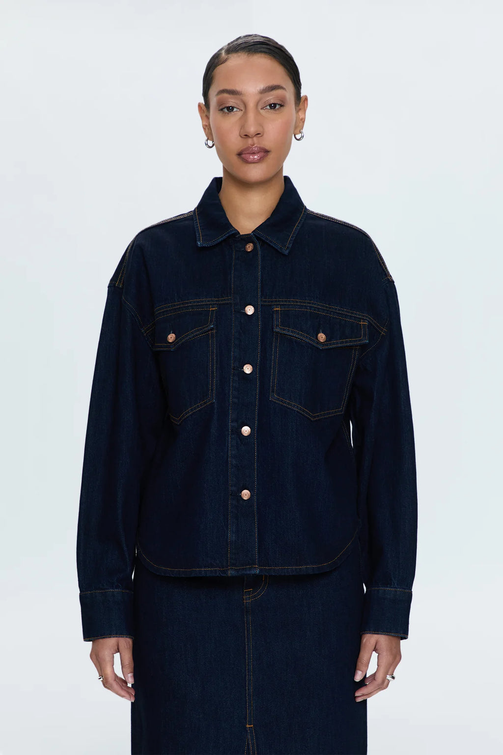 Menswear inspired, relaxed fit shacket designed for an oversized fit. Collared neckline, button up front closure, and front flap pockets.&nbsp;Crafted from rigid, lightweight denim without stretch for an expert fit that holds its shape.&nbsp;Countdown is a deep indigo rinse wash denim with contrast stitching and copper toned hardware.&nbsp;