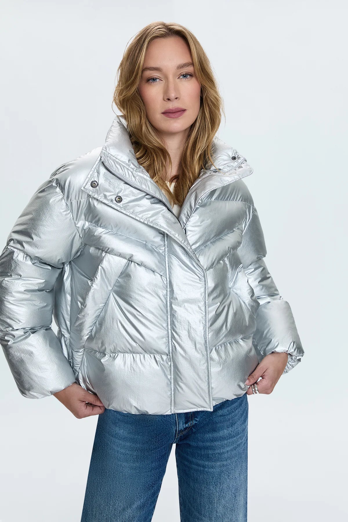 A lightweight nylon puffer jacket that hits right at the waist for a more feminine proportion. Designed with functional pocket, a collared neckline, and hidden zipper front closure. Disco is a high octane iridescent silver colorway with gunmetal hardware.