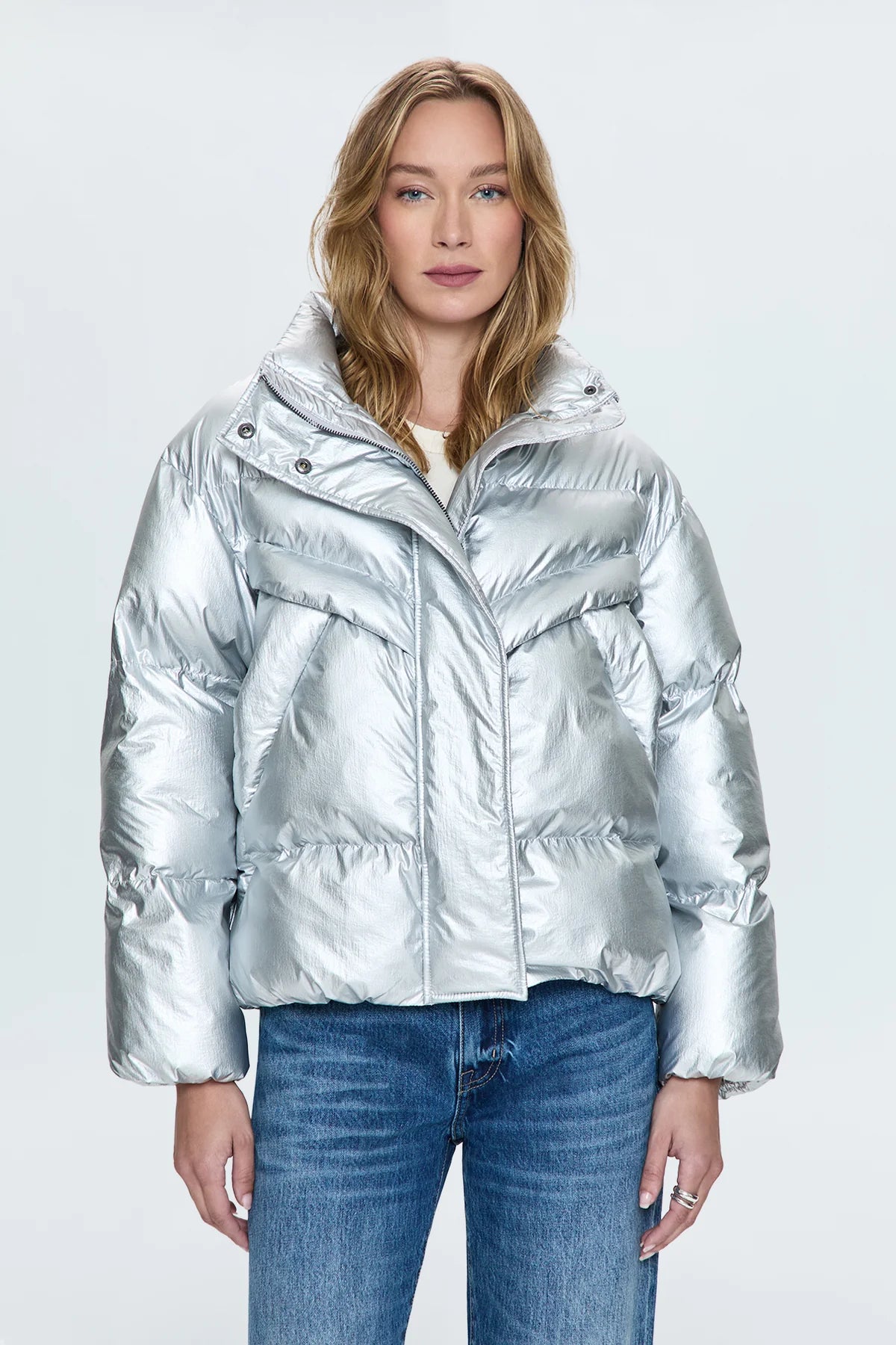 A lightweight nylon puffer jacket that hits right at the waist for a more feminine proportion. Designed with functional pocket, a collared neckline, and hidden zipper front closure. Disco is a high octane iridescent silver colorway with gunmetal hardware.