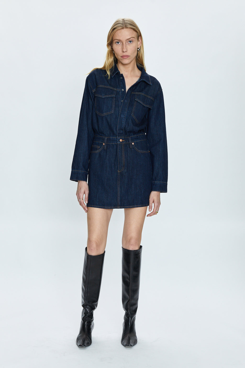 This denim on denim dress features a long sleeve button up top that flows into a raw hem mini skirt. In a true non stretch denim fabric, with functional pockets and belt loops.