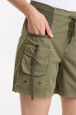 This premium poplin drawstring-waist short features a raw-edge contrast ribbed waistband, twill tape details, cargo pockets with ladder lock buckles, and antique brass eyelets throughout.