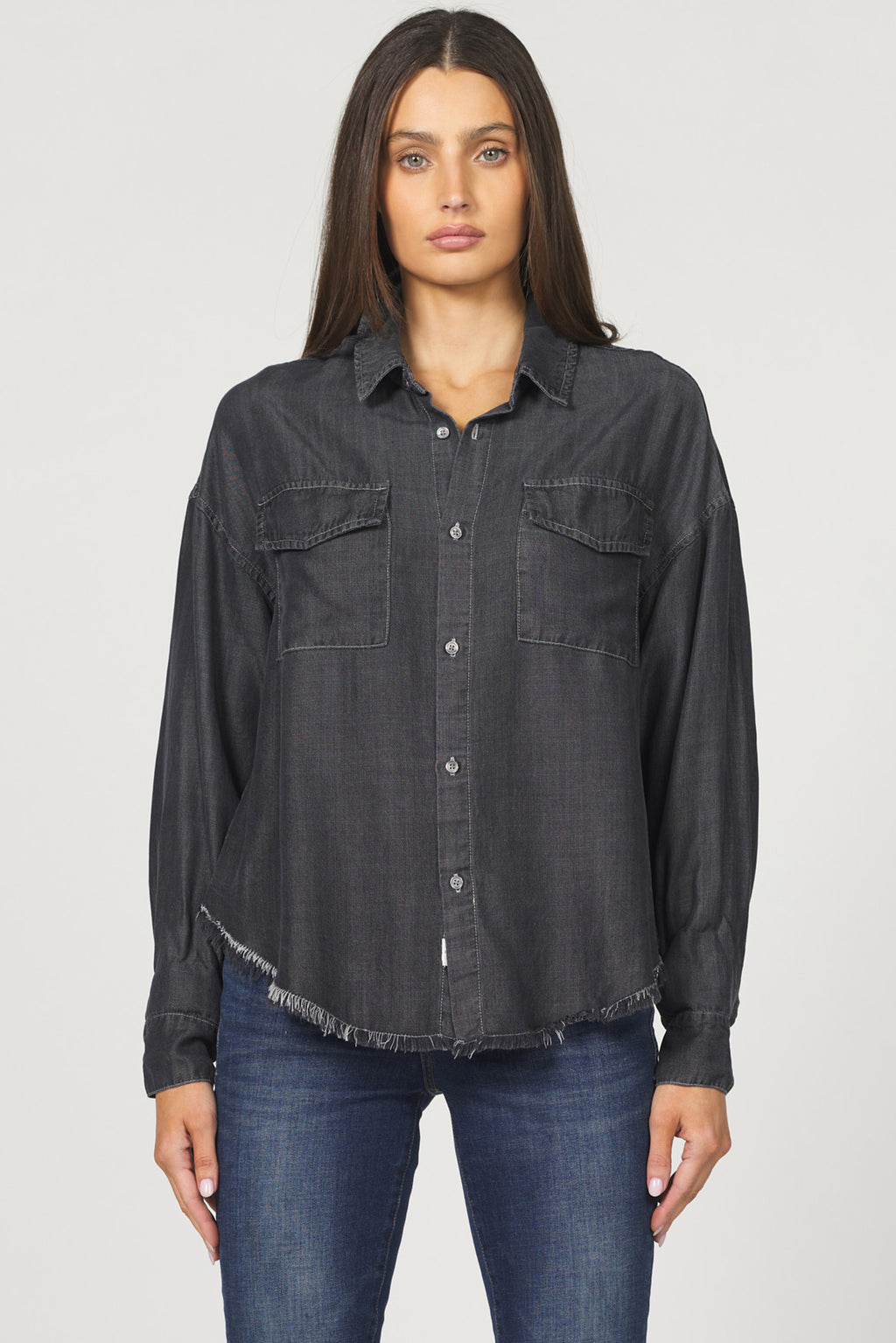 Woman wearing a black denim shirt and jeans on a white background