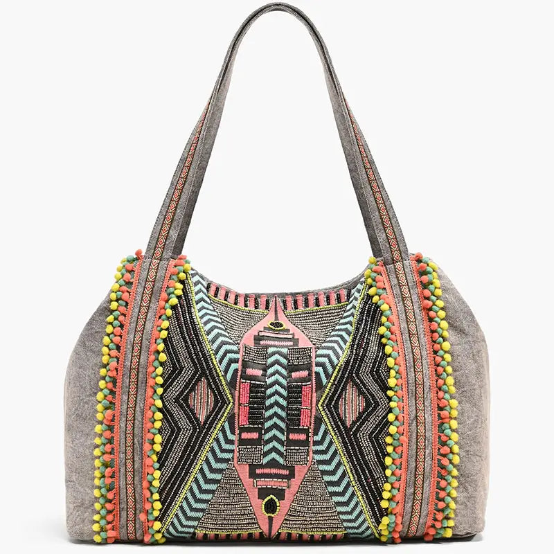Colorful handbag with geometric patterns and pom-pom details on a white background