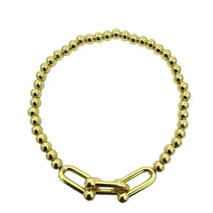Gold beaded bracelet with a clasp on a white background