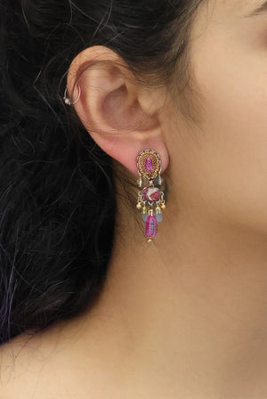 Close-up of an ear wearing a decorative earring with gemstones.
