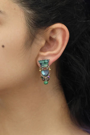 Close-up of an ear wearing a colorful earring with gemstones.