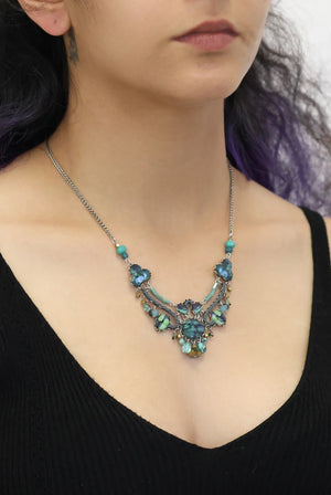 Necklace with blue gemstones worn by a person against a neutral background