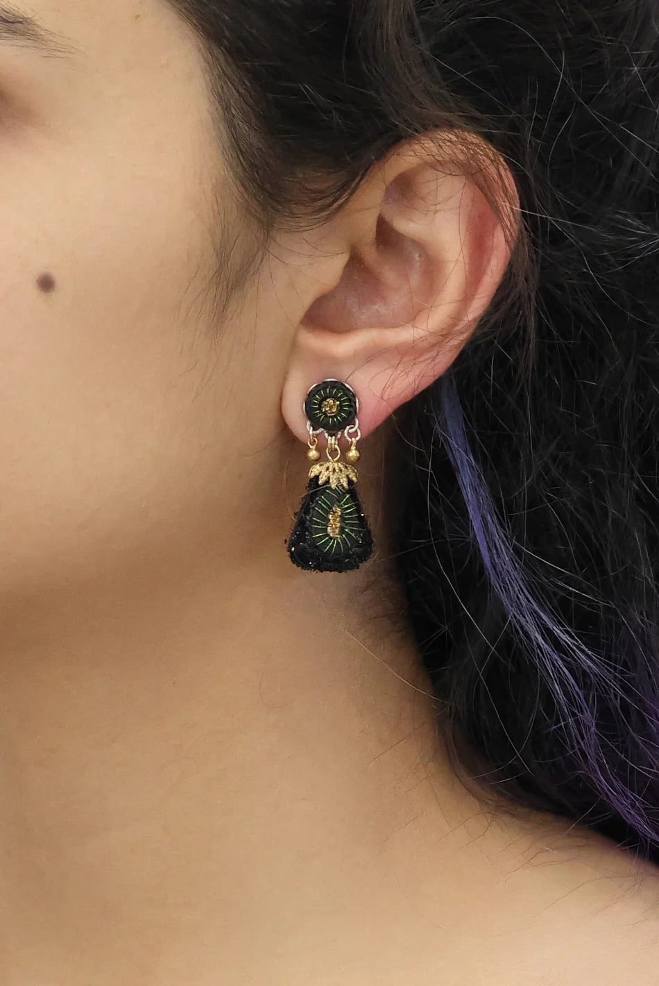 Close-up of an ear wearing a decorative earring with a blurred background
