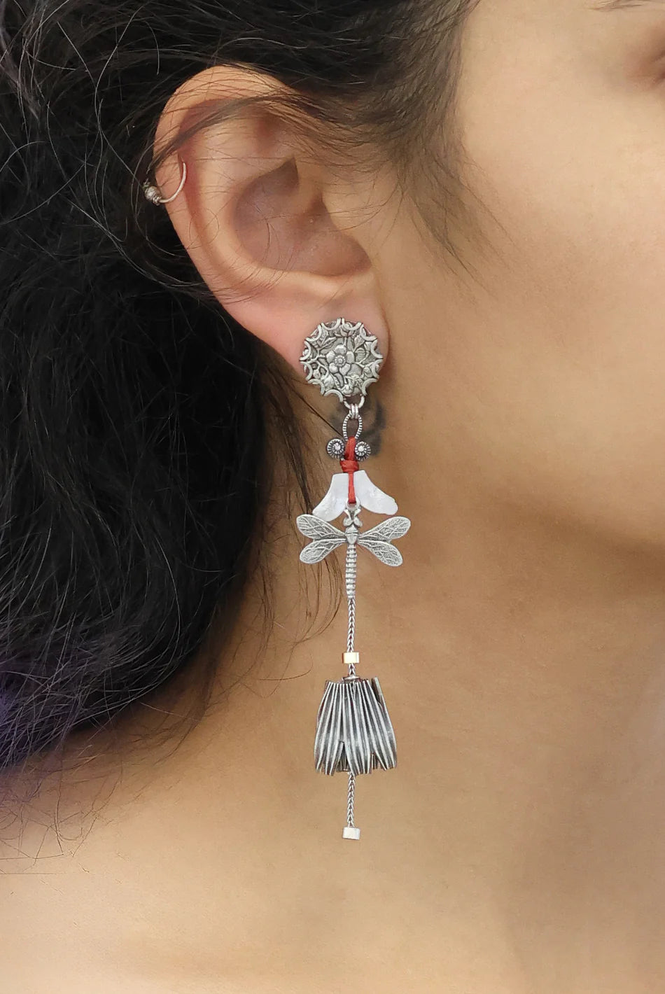 Close-up of an ear wearing a decorative earring with intricate design.