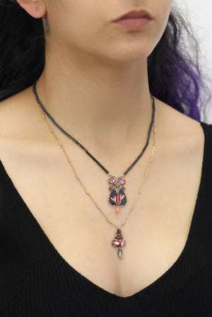 Close-up of a person wearing a necklace with heart-shaped pendants on a black background