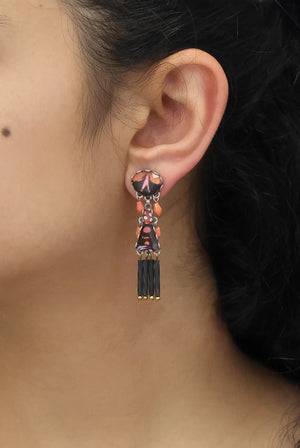 Close-up of an ear wearing a decorative earring with black and red details.