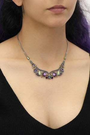 Necklace with colorful gemstones worn by a person against a black background