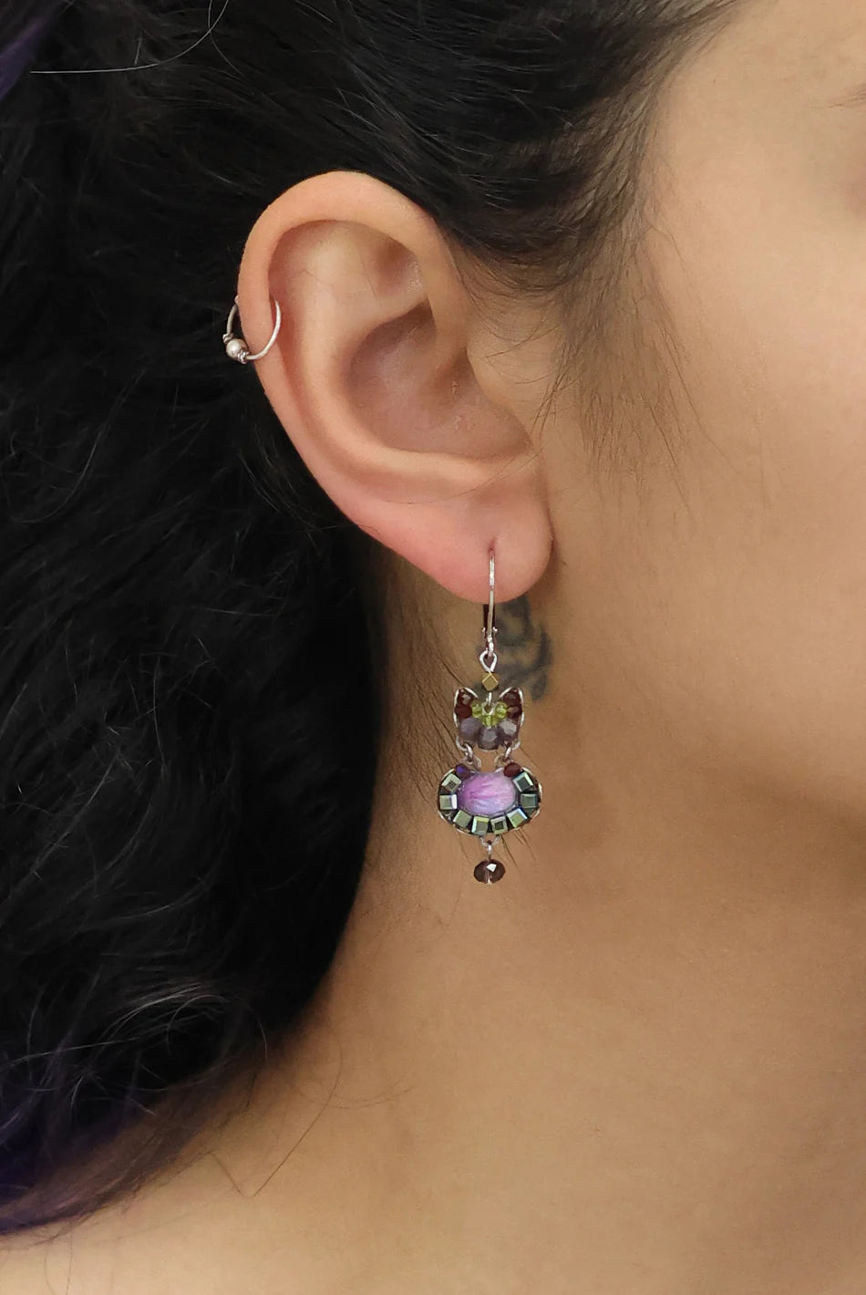 Close-up of an ear wearing a colorful earring with a blurred background