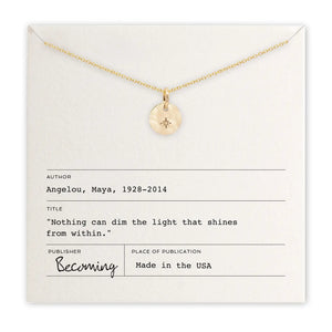 Gold necklace with a pendant on a card featuring text