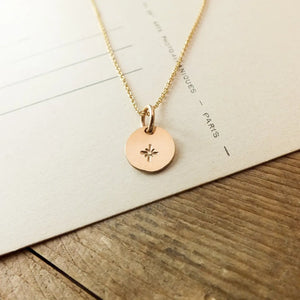 Gold necklace with a round pendant on a wooden surface