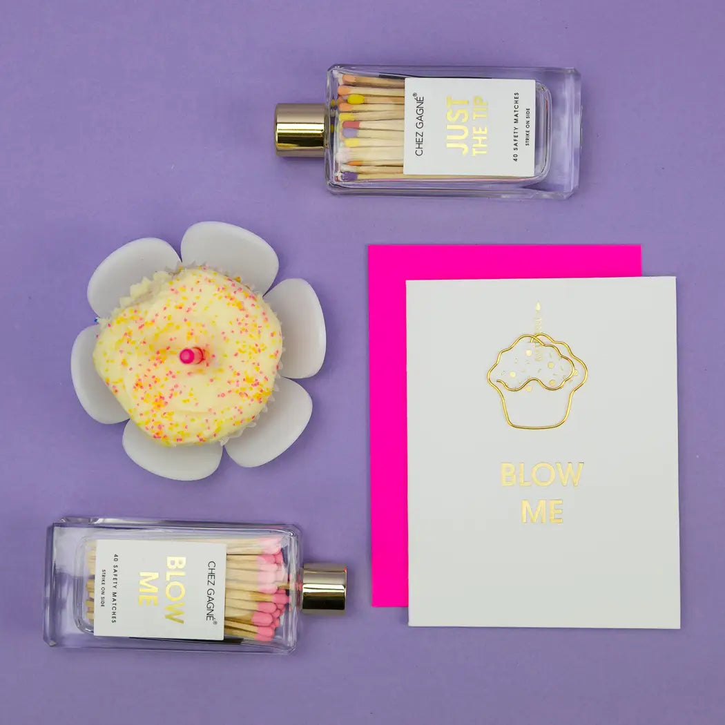 Matches in a bottle labeled 'Just for Me' and 'Blow Me' on a purple background with decorative items.
