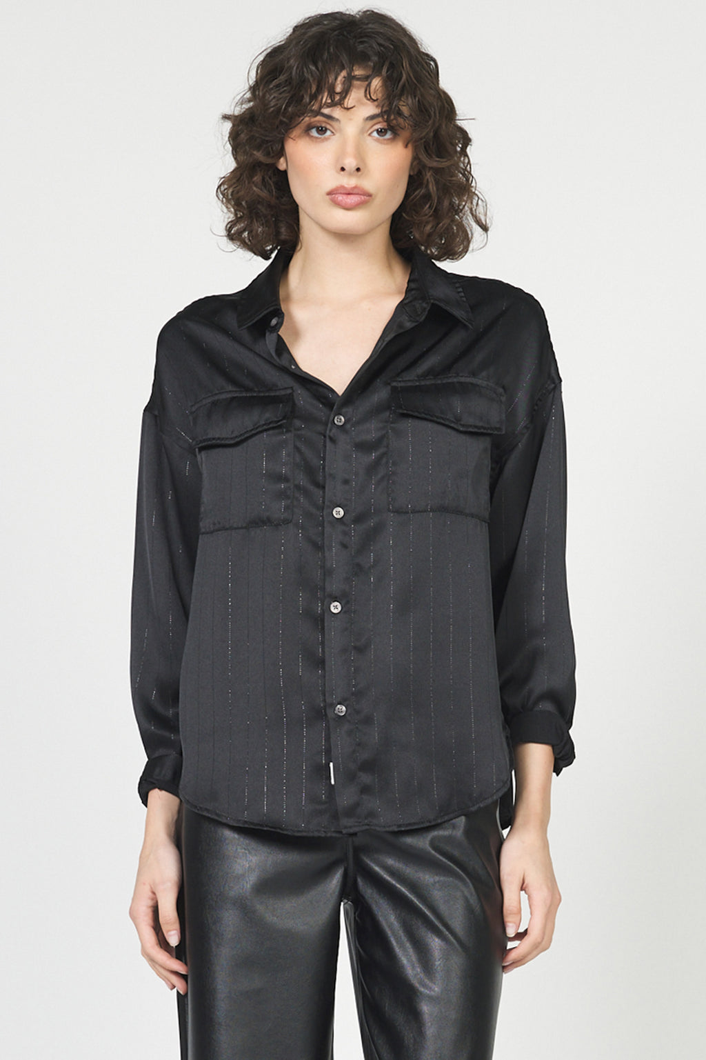 Woman wearing a black button-up shirt and black pants on a white background