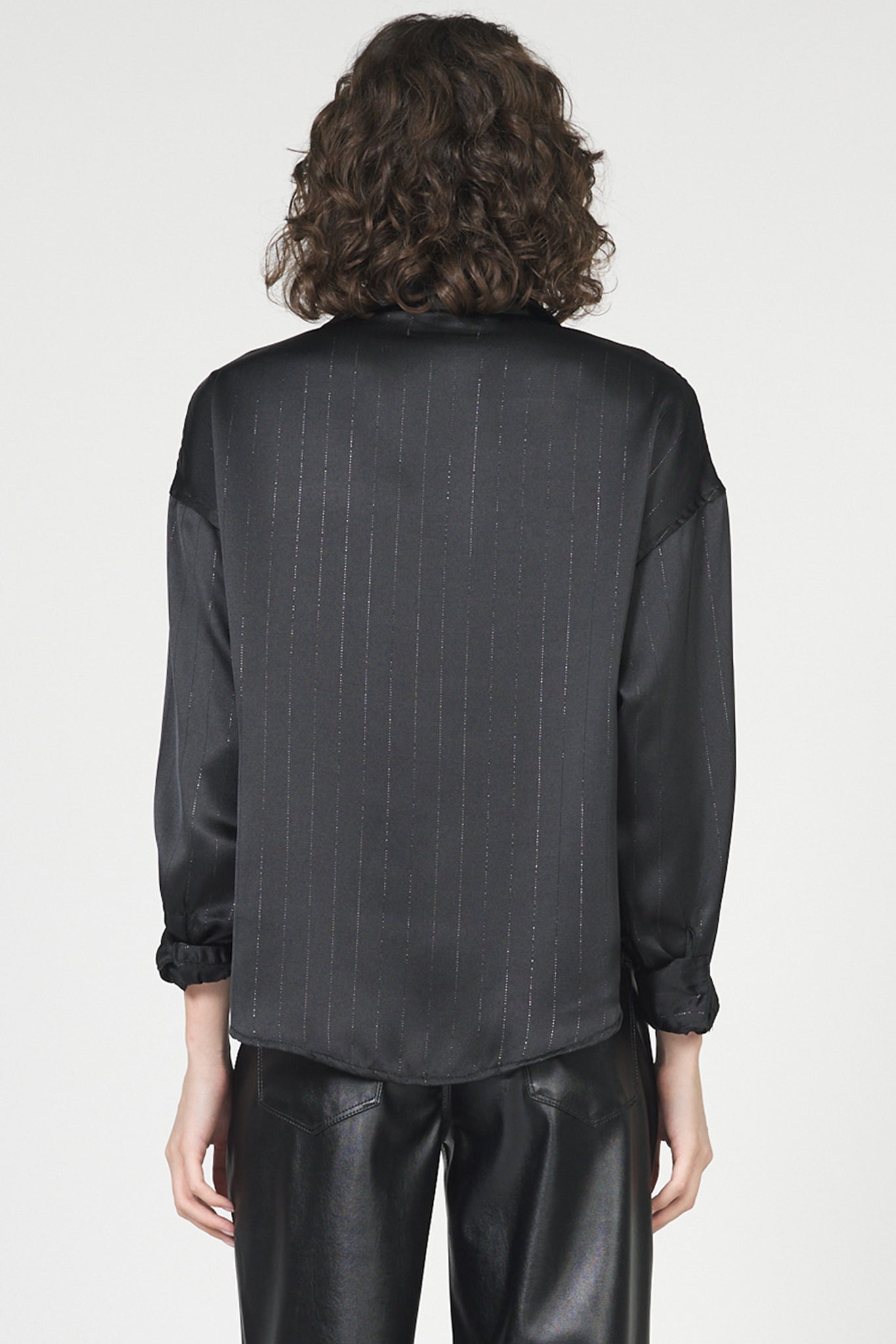 Person wearing a black pinstripe shirt and black pants on a white background