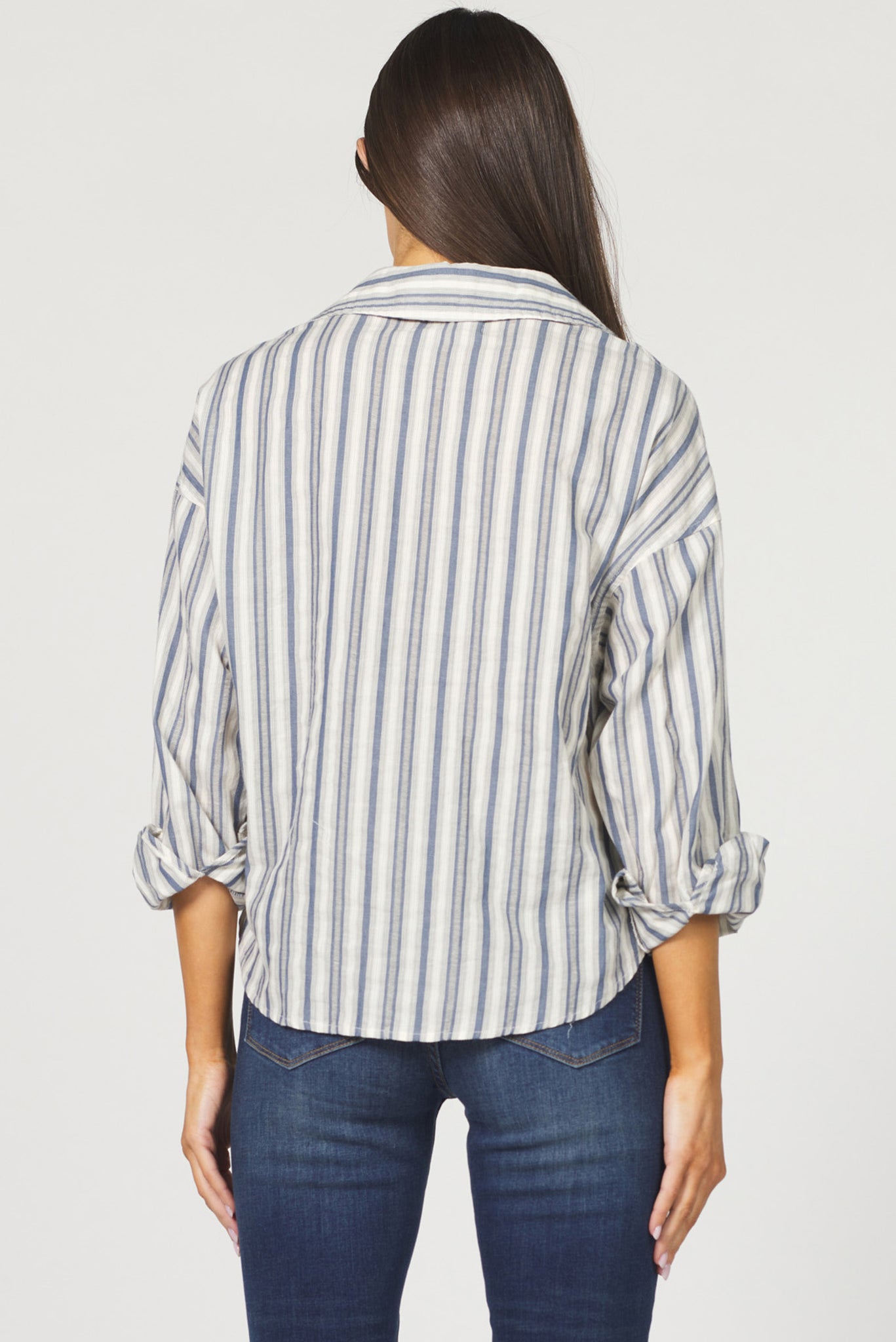 Woman wearing a striped shirt and jeans on a plain background
