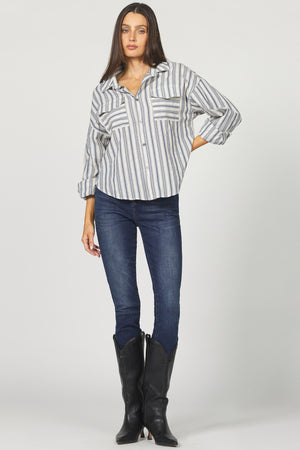 Woman wearing a striped shirt, blue jeans, and black boots on a white background