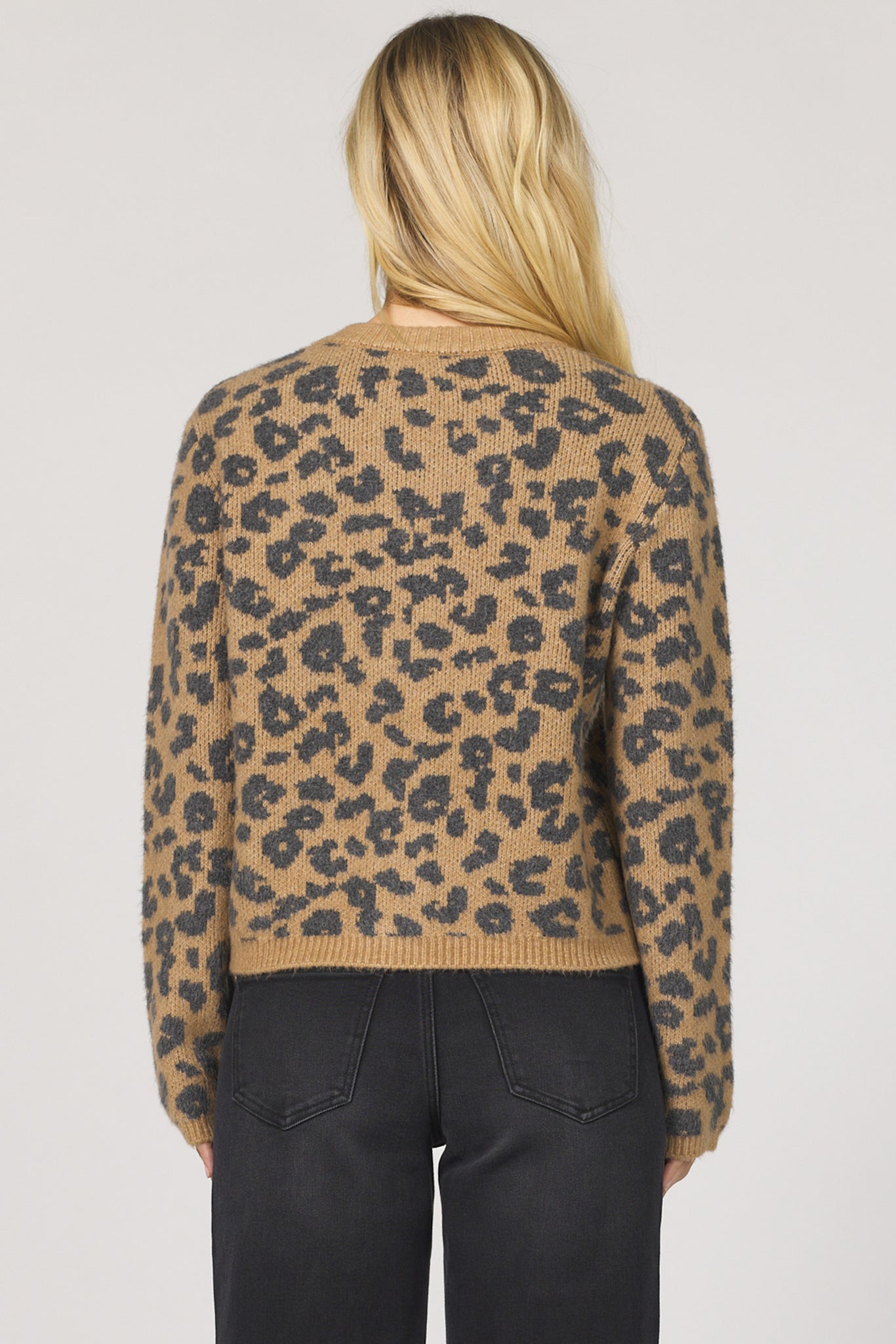 Person wearing a leopard print sweater on a plain background