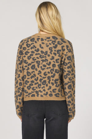 Person wearing a leopard print sweater on a plain background