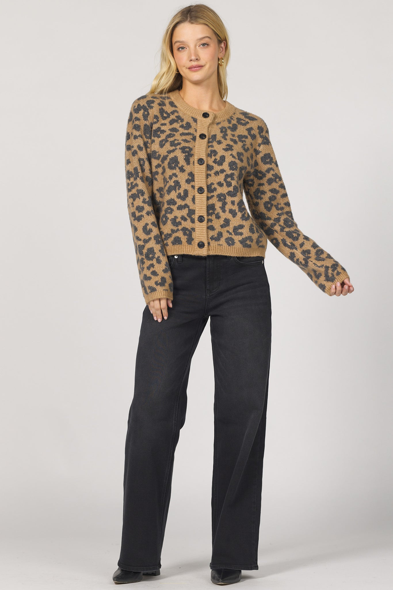 Woman wearing a leopard print jacket and black pants on a white background