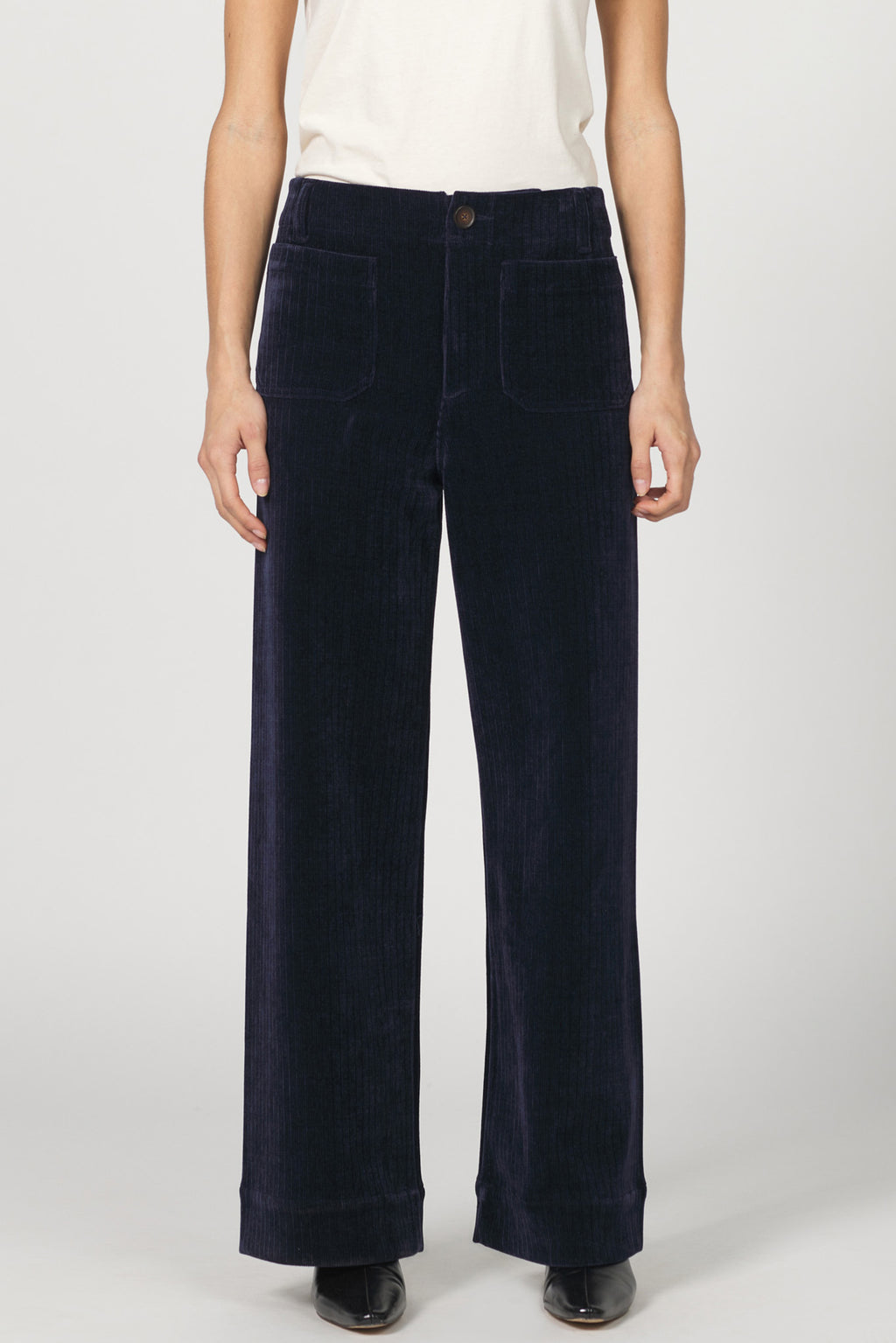 Navy blue corduroy pants worn by a person on a white background