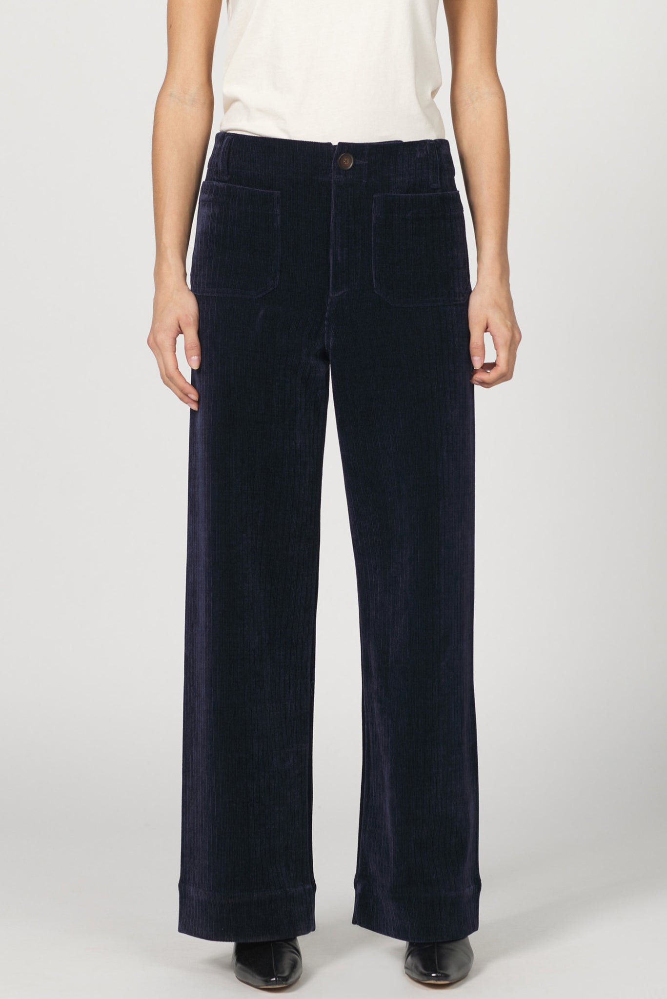 Navy blue corduroy pants worn by a person on a white background