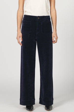 Navy blue corduroy pants worn by a person on a white background