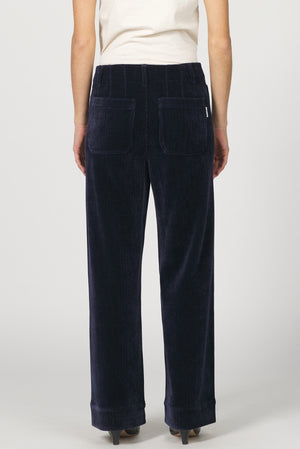 Navy blue corduroy pants worn by a person on a white background