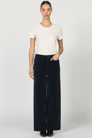 Woman wearing a white t-shirt and dark blue wide-leg pants on a white background
