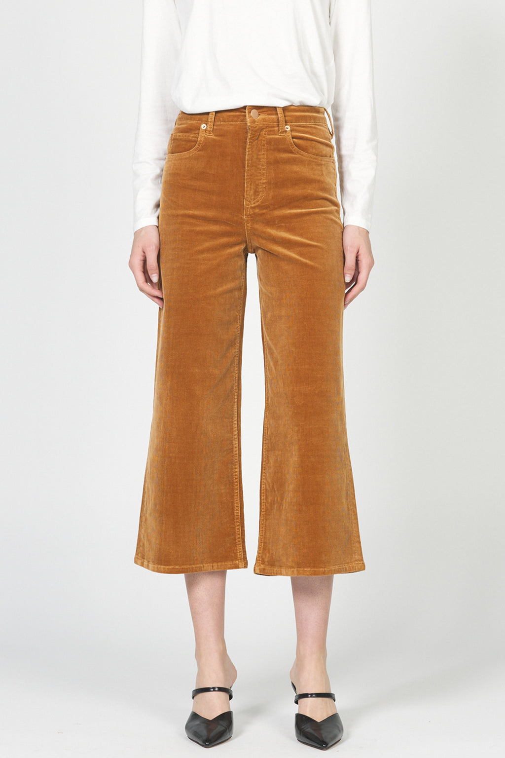 Brown corduroy pants worn by a person on a white background