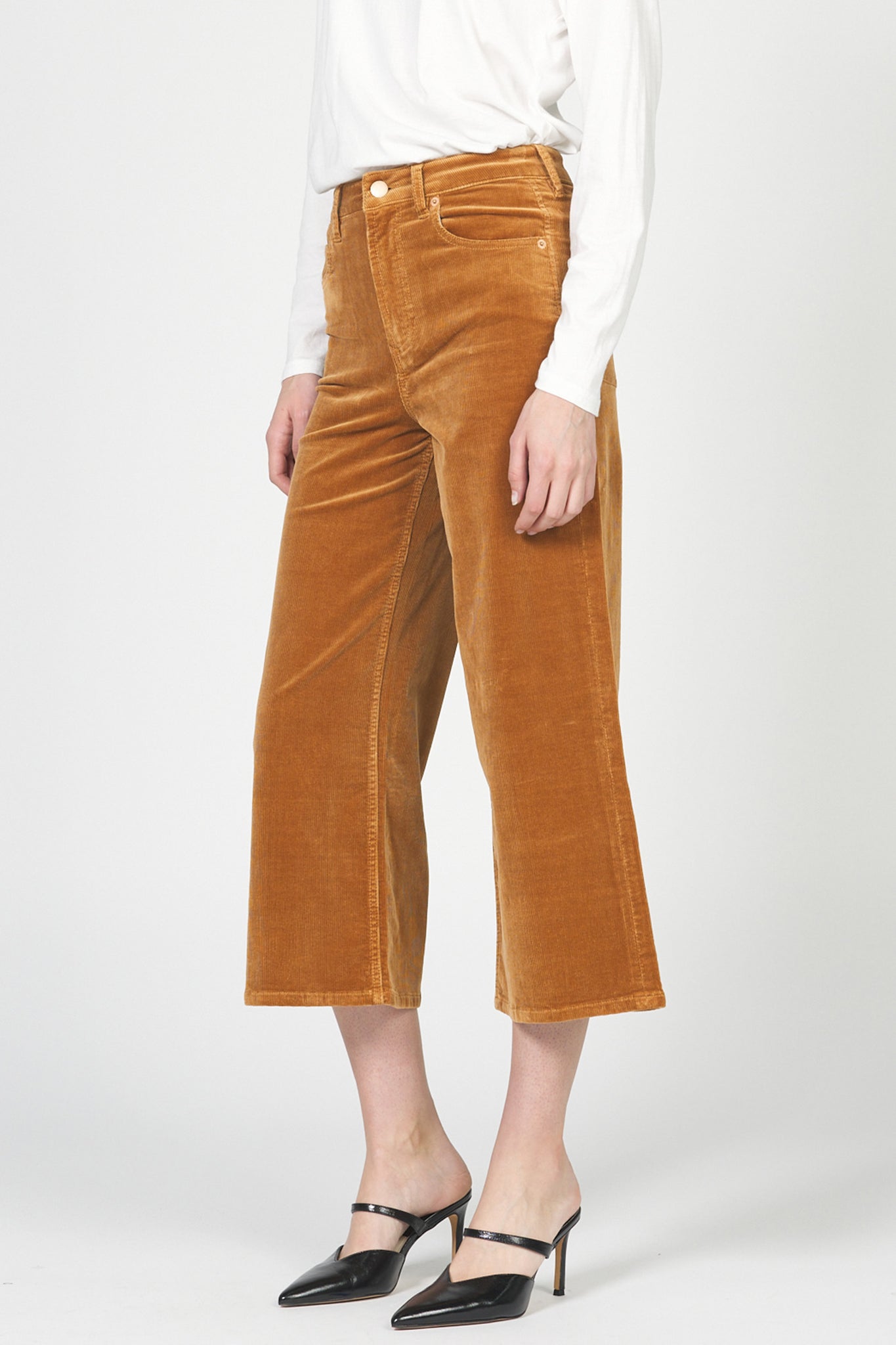 Person wearing brown velvet pants on a white background