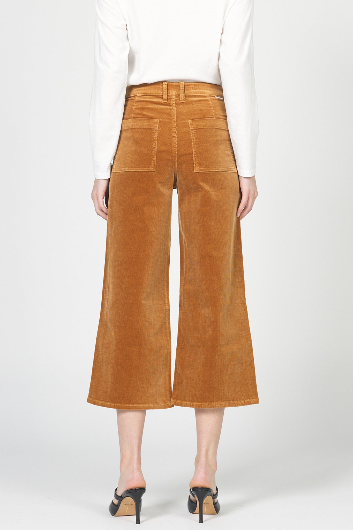 Brown corduroy pants worn by a person on a white background
