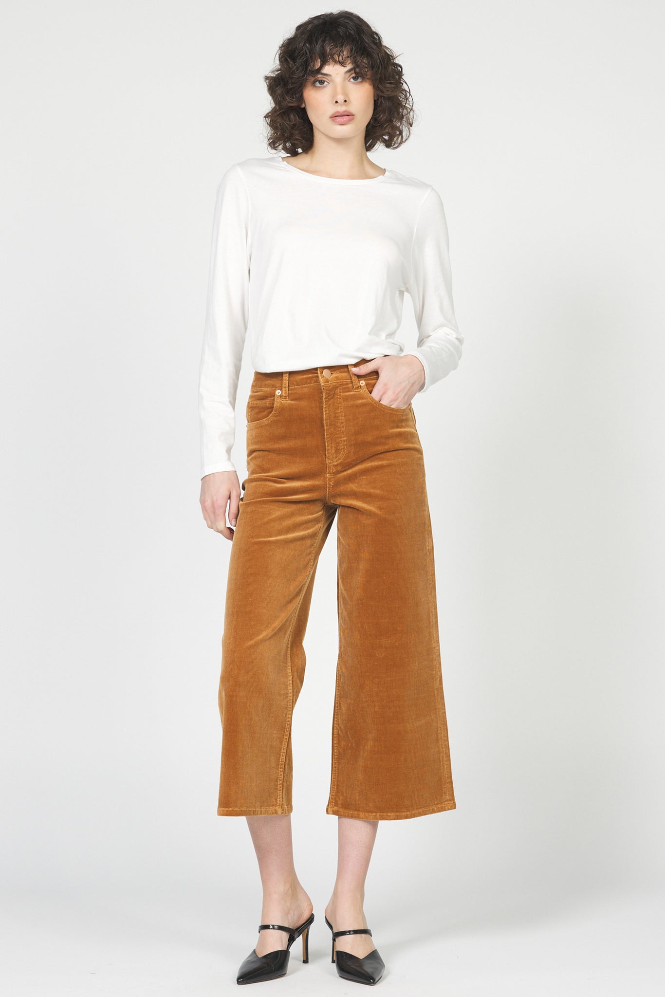 Woman wearing a white blouse and brown corduroy pants on a white background