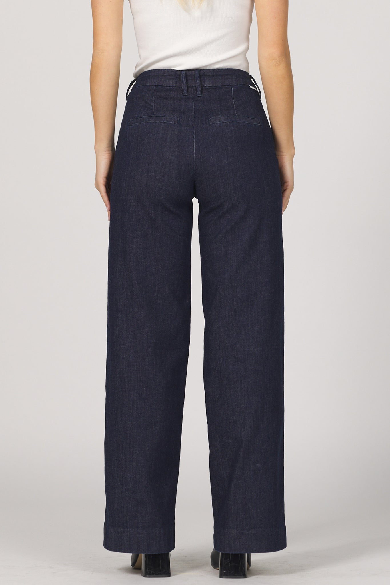 Navy blue pants worn by a person on a plain background