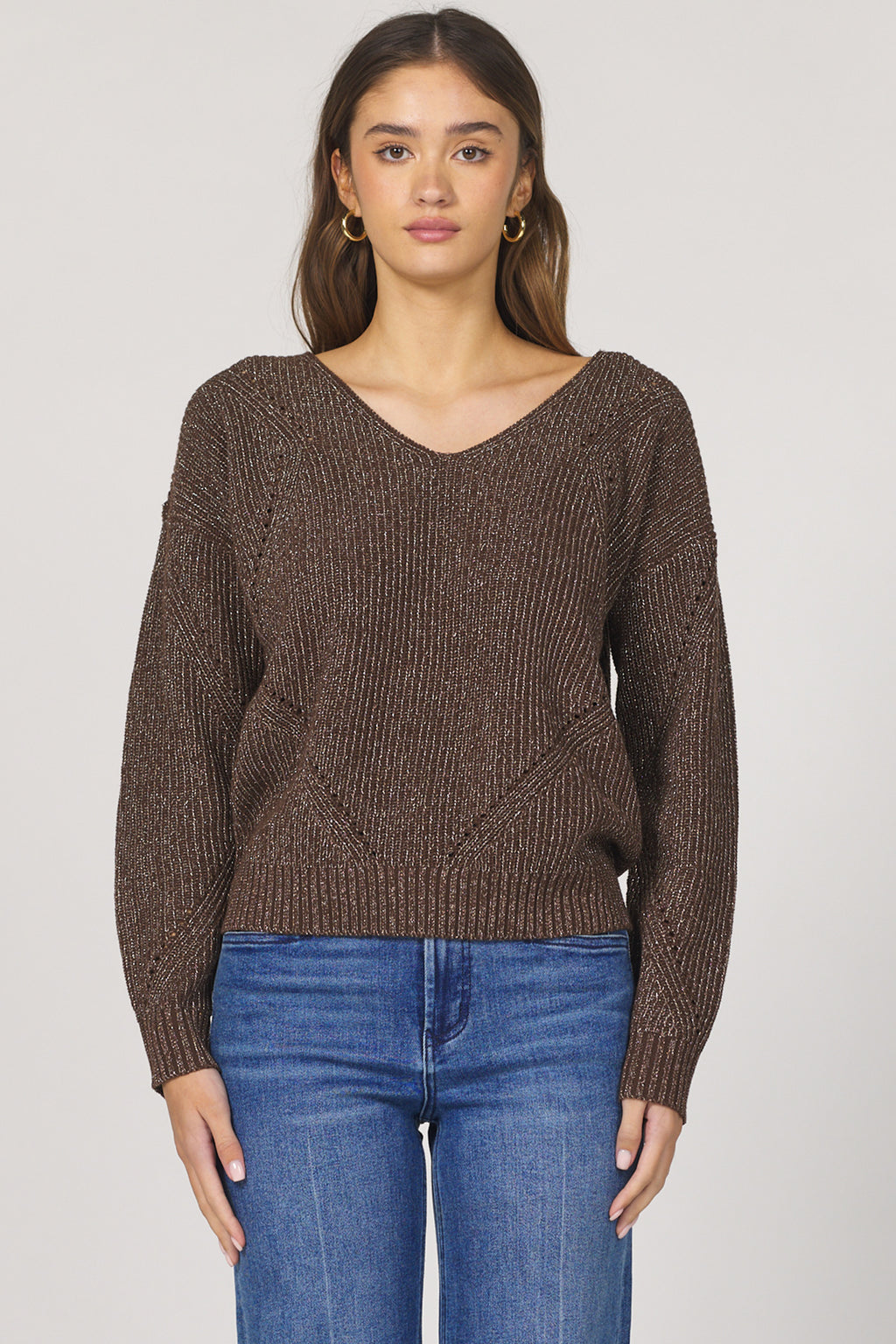 Woman wearing a brown knitted sweater and blue jeans on a white background