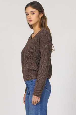 Woman wearing a brown knitted sweater and blue jeans on a white background