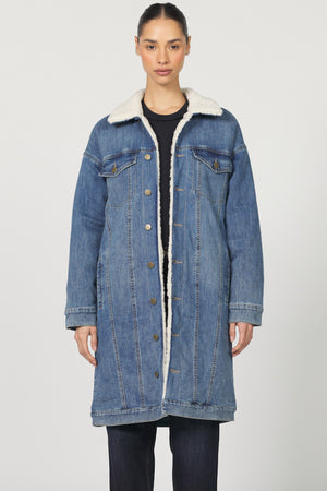 Denim coat with white fur lining worn by a model on a plain background