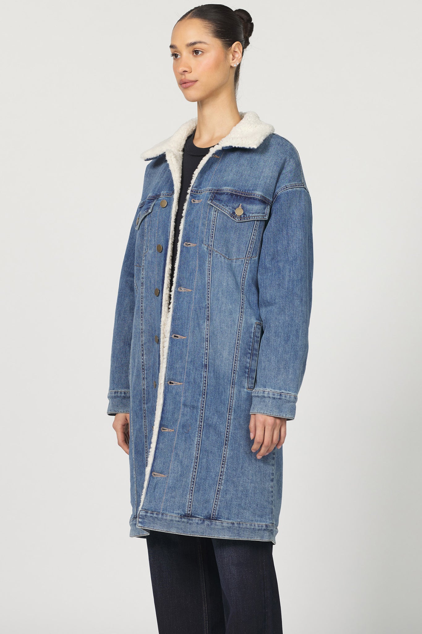 Woman wearing a blue denim coat with white fur lining on a white background
