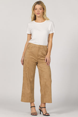 Woman wearing a white t-shirt and tan pants on a plain background
