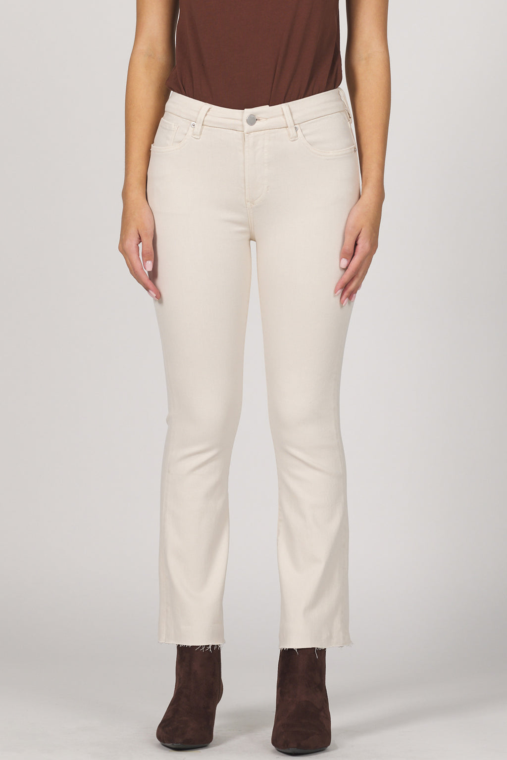 Person wearing white pants and brown shoes on a plain background