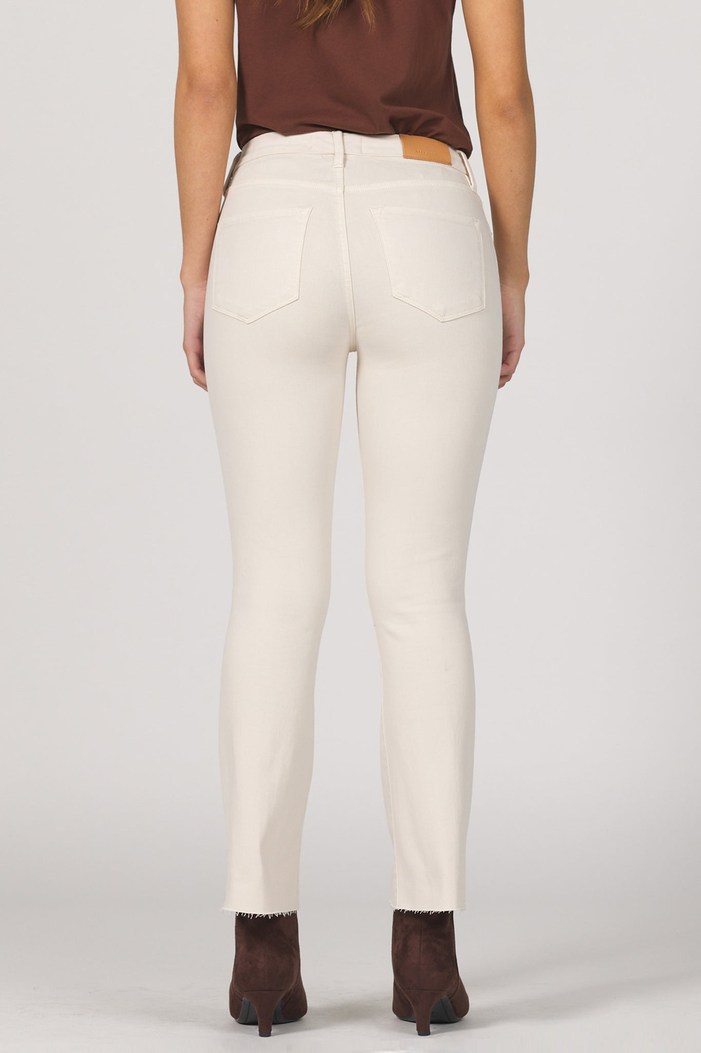 Person wearing white pants and brown shoes on a plain background