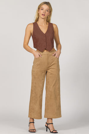 Woman wearing a brown vest and tan pants on a white background