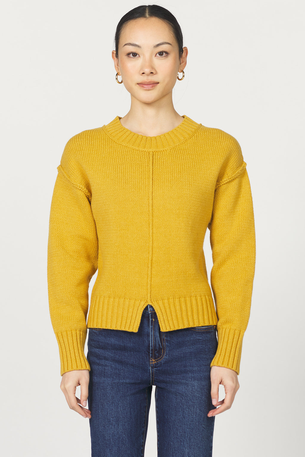 Person wearing a yellow sweater and blue jeans on a white background
