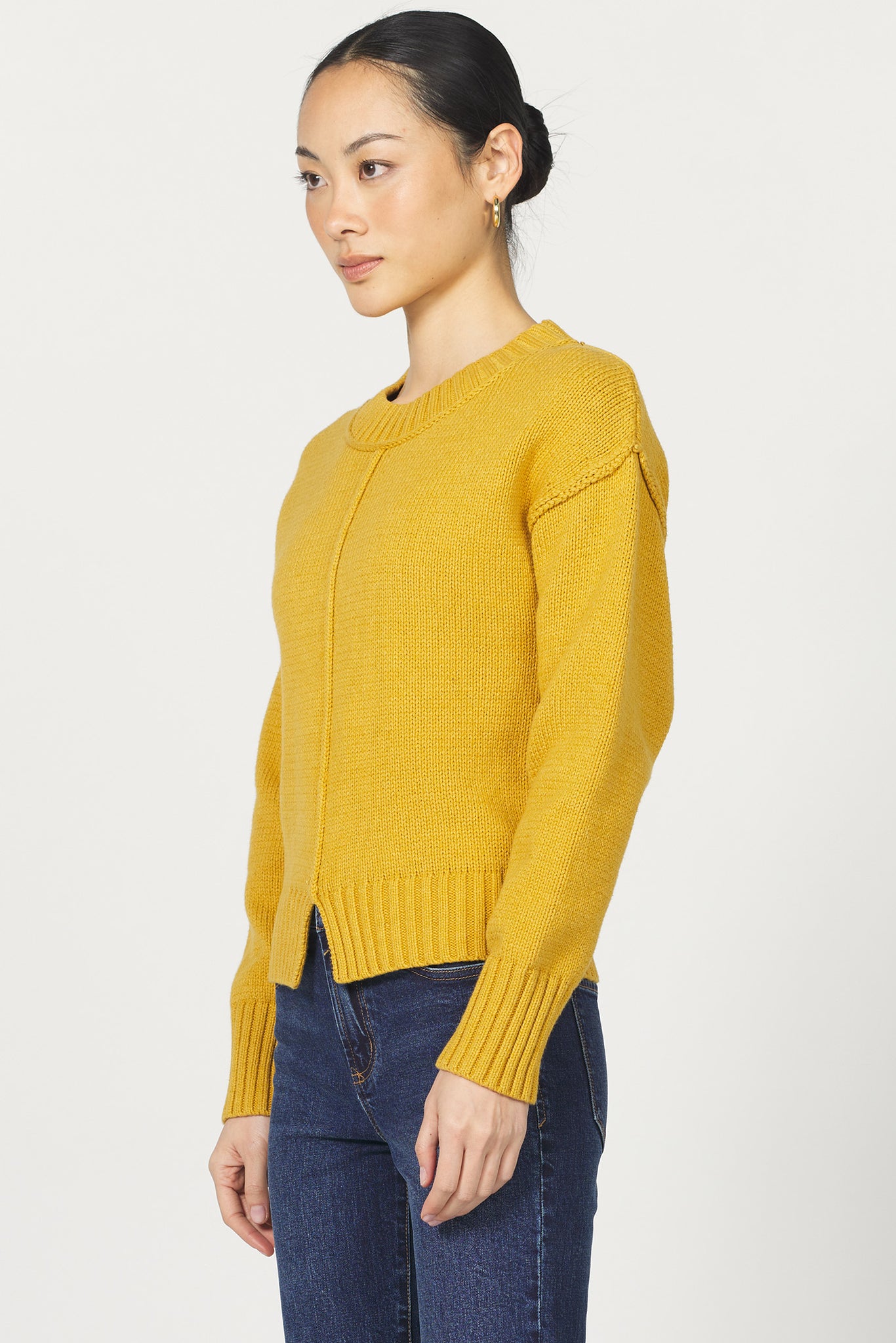 Person wearing a yellow sweater and blue jeans on a white background
